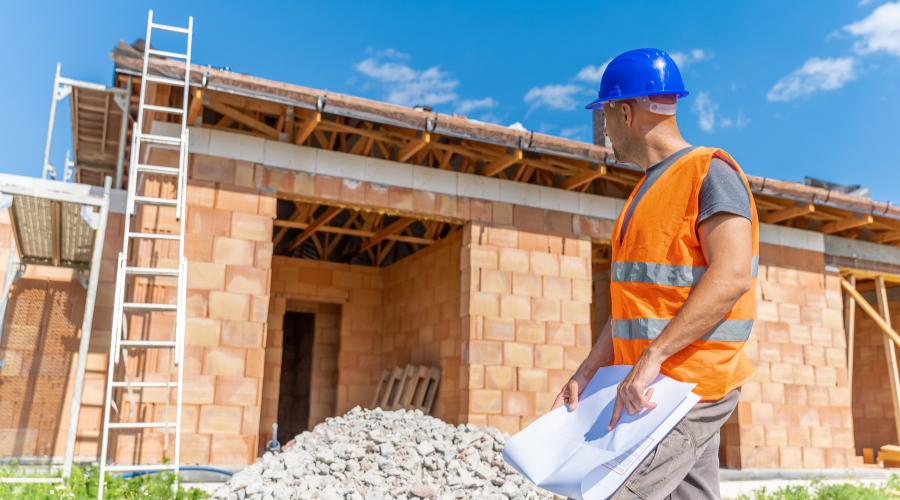 Engenheiro com planta em obra de construção financiada
